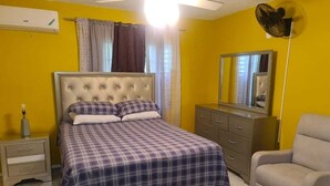 Une chambre à coucher avec un lit, une commode, une chaise et un ventilateur de plafond.