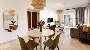 A modern living room with a round dining table, comfortable seating, a large mirror, and a television. - Punta Cana 2 Bedr. up to 6 guests 1 mile to Beach (Punta Cana)