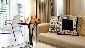 A modern living room with a beige sofa, patterned pillows, a coffee table with decorative items, and a floor lamp. - Punta Cana 2 Bedr. up to 6 guests 1 mile to Beach (Punta Cana)