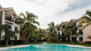 A resort with a swimming pool surrounded by palm trees and multi-story buildings with balconies. - Punta Cana 2 Bedr. up to 6 guests 1 mile to Beach (Punta Cana)