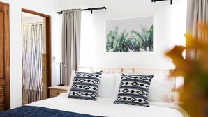 A neatly made bed with patterned pillows, a bedside table with a lamp, and a wall-mounted curtain rod. - Punta Cana 2 Bedr. up to 6 guests 1 mile to Beach (Punta Cana)