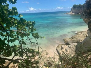 A coastal landscape with clear turquoise water, rocky shore, and vegetation. - Punta Cana 2 Bedr. up to 6 guests 1 mile to Beach (Punta Cana)