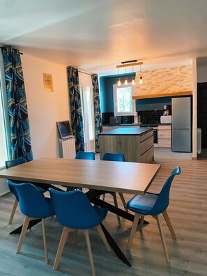 A modern kitchen with a wooden island, blue chairs, and a dining table.