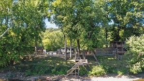 Una cabana al costat d'un llac amb terrassa de fusta, un petit moll i una escala que mena a una zona de terrassa.