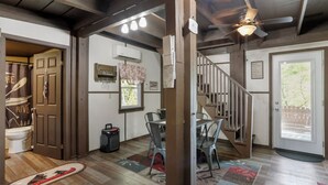 Una habitació àmplia amb terra de fusta, una escala i una porta que dona a un bany.