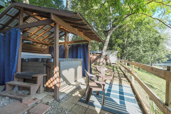 A covered outdoor grill area with steps leading up to it, a picnic table, and a wooden fence surrounding the space. - Waterfront Cabin overlooking the Potomac River W/ Hot Tub, firepit, pavilion (Hedgesville)