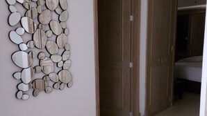 A hallway with a wall-mounted mirror art piece, wooden doors, and a tiled floor. - Paradise apartment in beach condo Bay View Grand (Puerto Vallarta)