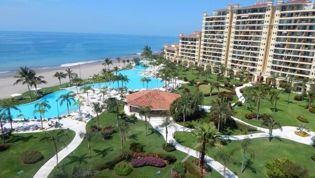 A resort with a large pool, palm trees, and a beach view. - Paradise apartment in beach condo Bay View Grand (Puerto Vallarta)