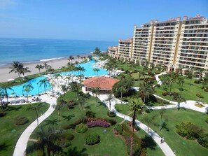 A resort with a large pool, palm trees, and a beach view. - Paradise apartment in beach condo Bay View Grand (Puerto Vallarta)
