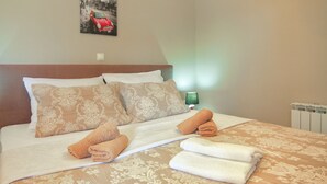 Una cama bien hecha con ropa de cama estampada, dos almohadas y toallas dobladas.
