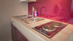 Una cocina moderna con dos fregaderos, una estufa de acero inoxidable y un salpicadero rojo.