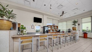 A modern bar area with a long counter, multiple bar stools, and a variety of items on shelves.