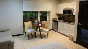 A compact kitchen with white cabinets, a microwave, and a coffee maker. There is a small dining area with a table and two chairs.