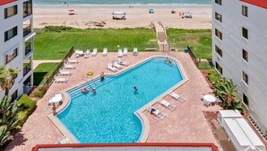 Una piscina con sillas de descanso y vistas a la playa.