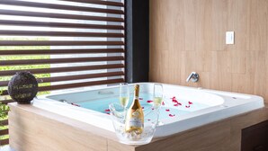 A modern bathroom with a large bathtub, a bottle of champagne, and two glasses.