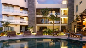A modern hotel with a pool, outdoor seating, and a well-lit patio area.