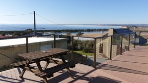 A wooden deck with a picnic table overlooking a coastal landscape.