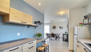 A modern kitchen with a blue accent wall, wooden cabinetry, and a dining area with a chandelier.