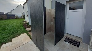 Een modern gebouw met een grijze gevel, een witte deur en een klein raam.