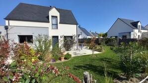 Een woonwijk met moderne huizen, een verzorgd gazon en diverse beplanting.