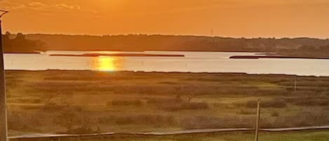 A sunset over a body of water with a flat landscape in the foreground.