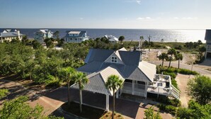 A coastal property with a large house featuring a covered patio and a view of the ocean. - Steps to Beach | Sleeps 12, Game Room & Bay Views in Windmark | Boat Parking (Port St Joe)