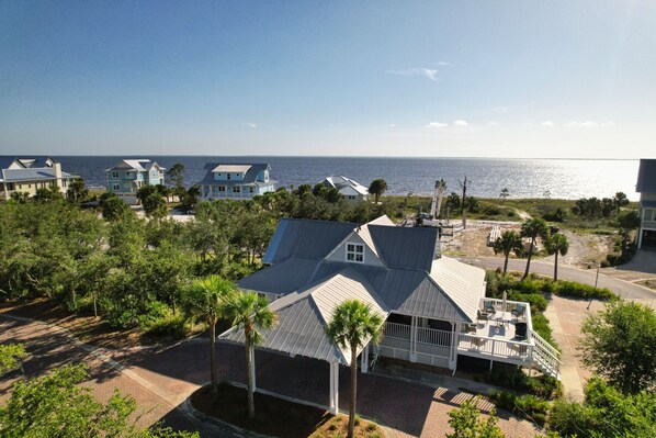 A coastal property with a large house featuring a covered patio and a view of the ocean. - Steps to Beach | Sleeps 12, Game Room & Bay Views in Windmark (Port St Joe)