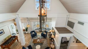 A spacious loft with a high ceiling, a central wooden column, and a cozy seating area with sofas and a coffee table. - Steps to Beach | Sleeps 12, Game Room & Bay Views in Windmark | Boat Parking (Port St Joe)