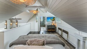 A bedroom with a large bed, a hanging light fixture, and a view of the outside. - Steps to Beach | Sleeps 12, Game Room & Bay Views in Windmark | Boat Parking (Port St Joe)