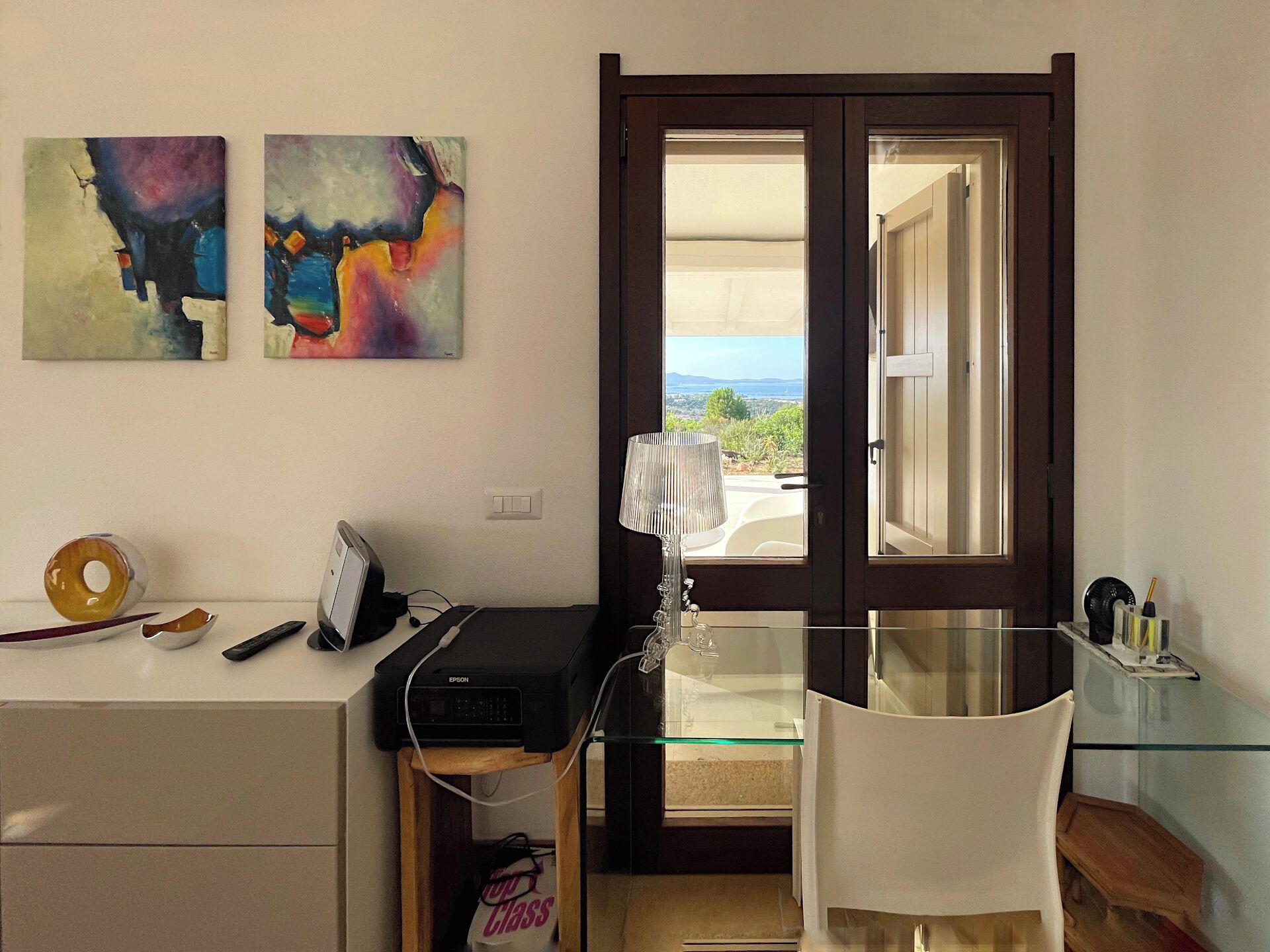 Ein Homeoffice mit Schreibtisch, Drucker und zwei abstrakten Bildern an der Wand.
