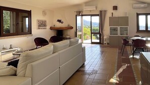 Un salón espacioso con un sofá blanco, una mesa de comedor con sillas y una zona de cocina.