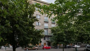 A multi-story residential building with balconies, parked cars, and trees in a residential area. - Luxury spacious apartment in the center (Hlavní mesto Praha)