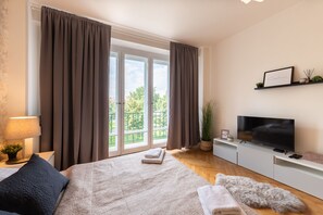 A modern bedroom with a large bed, a TV, and a balcony with curtains.