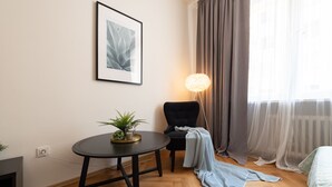 A cozy room with a round table, a chair, a bed, a lamp, and a window with curtains. - Luxury spacious apartment in the center (Hlavní mesto Praha)