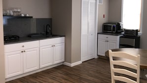 Una cucina compatta con mobili bianchi, un forno a microonde e una ventola a soffitto.