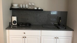 Una cucina compatta con mobili bianchi, un piano di lavoro in granito e un pavimento in legno.