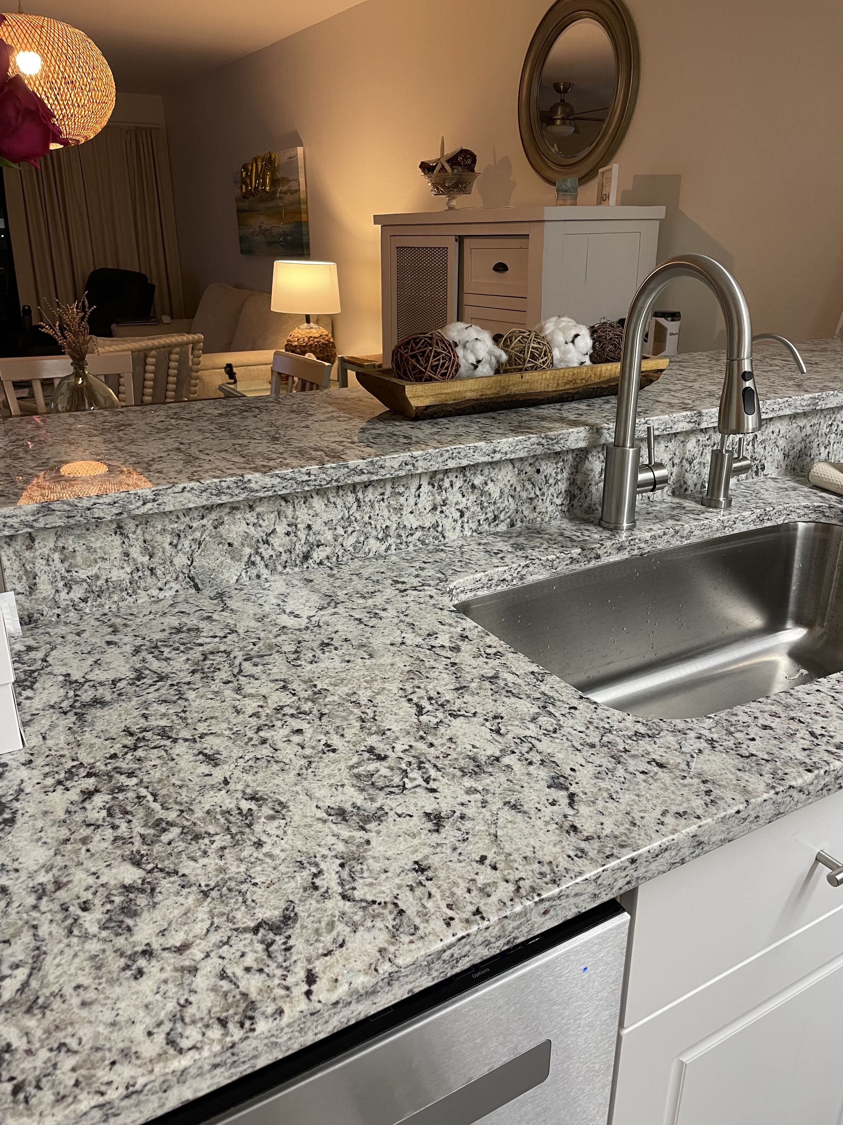 A kitchen with granite countertops, stainless steel sink, and modern faucet.
