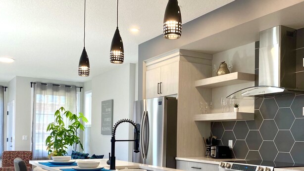 Et moderne køkken med en central ø, rustfrie hårde hvidevarer og en backsplash med hexagonfliser.