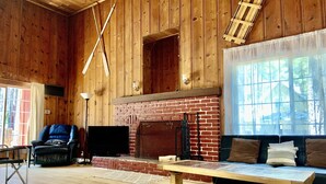 Ein rustikales Holzinterieur mit Kamin aus Backstein, einem Ledersessel, einer Couch und einem Holztisch.