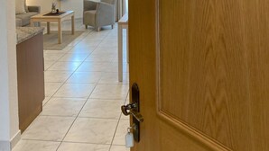 Una camera d'albergo con una porta in legno, vista sull'area soggiorno e un'immagine di montagna sulla porta.