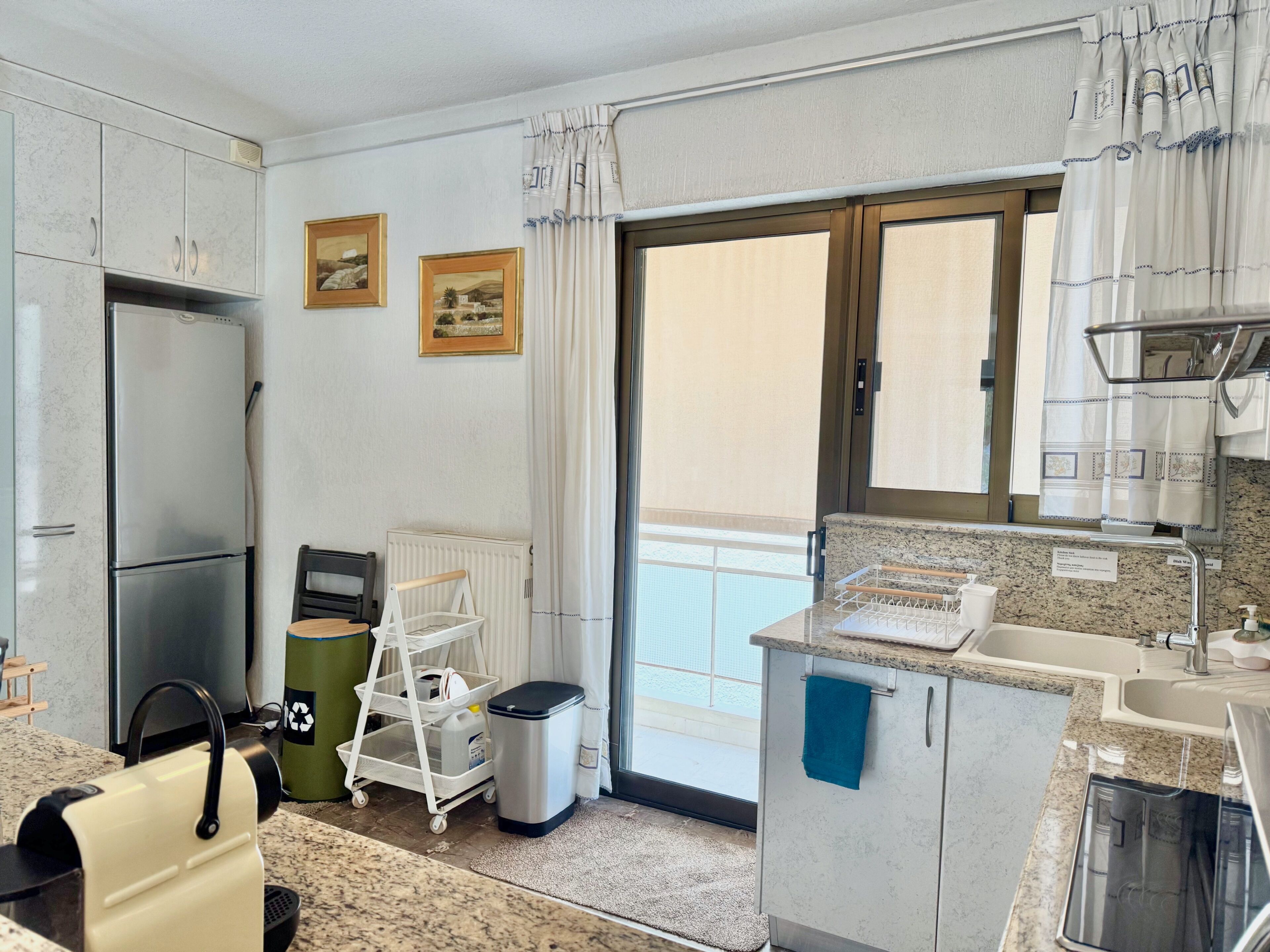 A compact kitchen with a refrigerator, sink, and a small dining area.