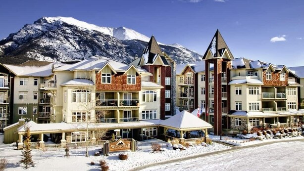 Een hotel met meerdere verdiepingen, een opvallende toren en een berg op de achtergrond.