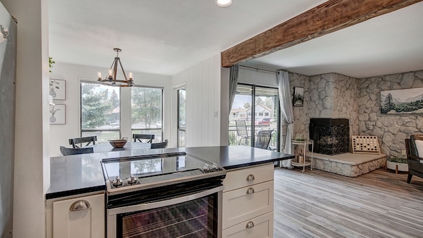 A modern kitchen with a large island, a stone fireplace, and a dining area with a view of the outdoors. - Luxurious Lakefront Haven - Prime Ski Access & Majestic Mountain Views! (Dillon)