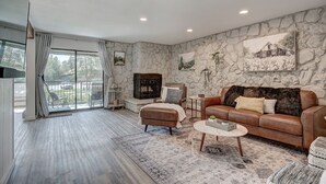 A spacious living room with a stone wall, a leather sofa, a coffee table, and a fireplace. - Luxurious Lakefront Haven - Prime Ski Access & Majestic Mountain Views! (Dillon)