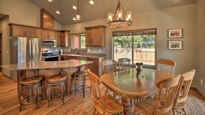 A spacious kitchen with a central island, wooden chairs, and a chandelier. - Rustic Cabin Near Mt Rainier: Fire Pit & BBQ! (Packwood)