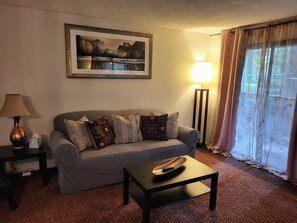 A living room with a sofa, a coffee table, a lamp, a picture frame, and a floor lamp.