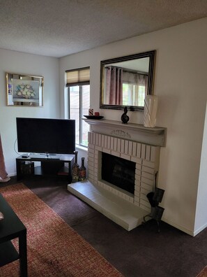 A living room with a fireplace, a television, and a framed picture on the wall.