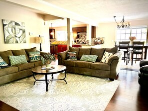 A living room with a brown sectional sofa, a round coffee table, and patterned rugs.