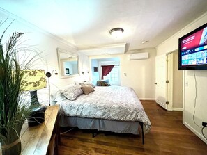 A bedroom with a bed, a TV mounted on the wall, and a potted plant. - Riverfront on the Rogue! Ideal Southern Oregon location (Gold Hill)