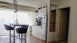 Cocina compacta con refrigerador, estufa y taburetes de bar.